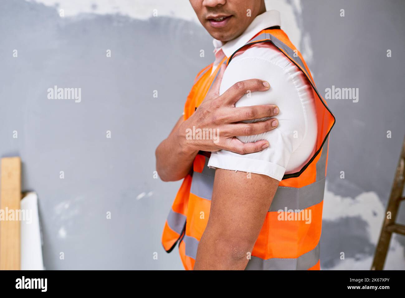 Bauarbeiter hält die Schulter bei Schmerzen durch Verletzungen am Arbeitsplatz auf der Baustelle Stockfoto