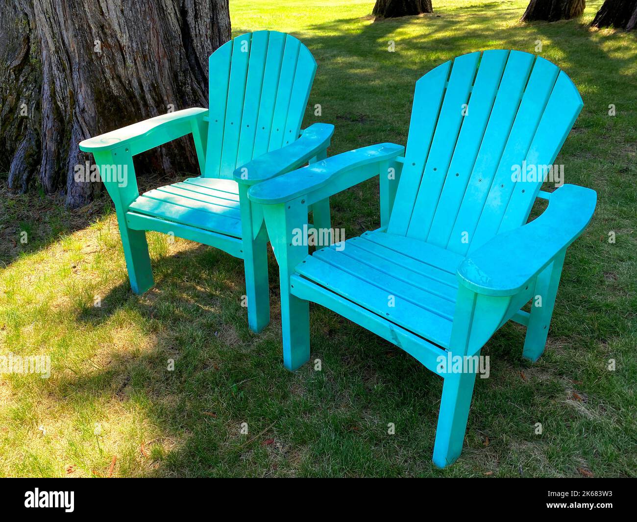 Ein Hinterhof Lounge Stühle schattig entspannend grün alten Stuhl Sitzgelegenheiten Garten Gras Schatten Bäume Retro-Design Vintage-Stil Holz Strand im Freien blauen Sessel gr Stockfoto