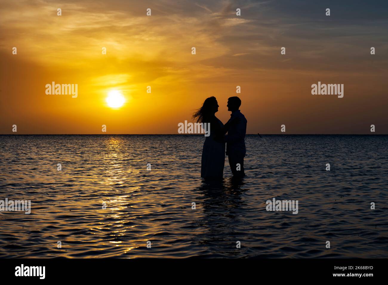 Junges, liebevolles Paar bei Sonnenuntergang in der Karibik. Stockfoto