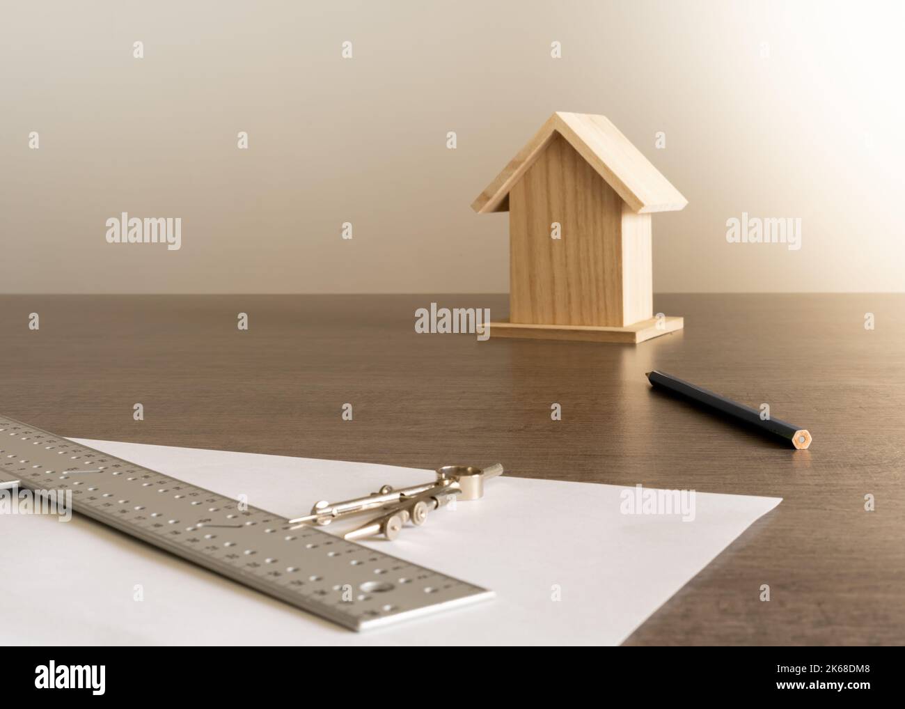 Objekte auf dem Tisch im Büro eines Architekten mit einem kleinen Holzhaus im Hintergrund zur Dekoration. Stockfoto
