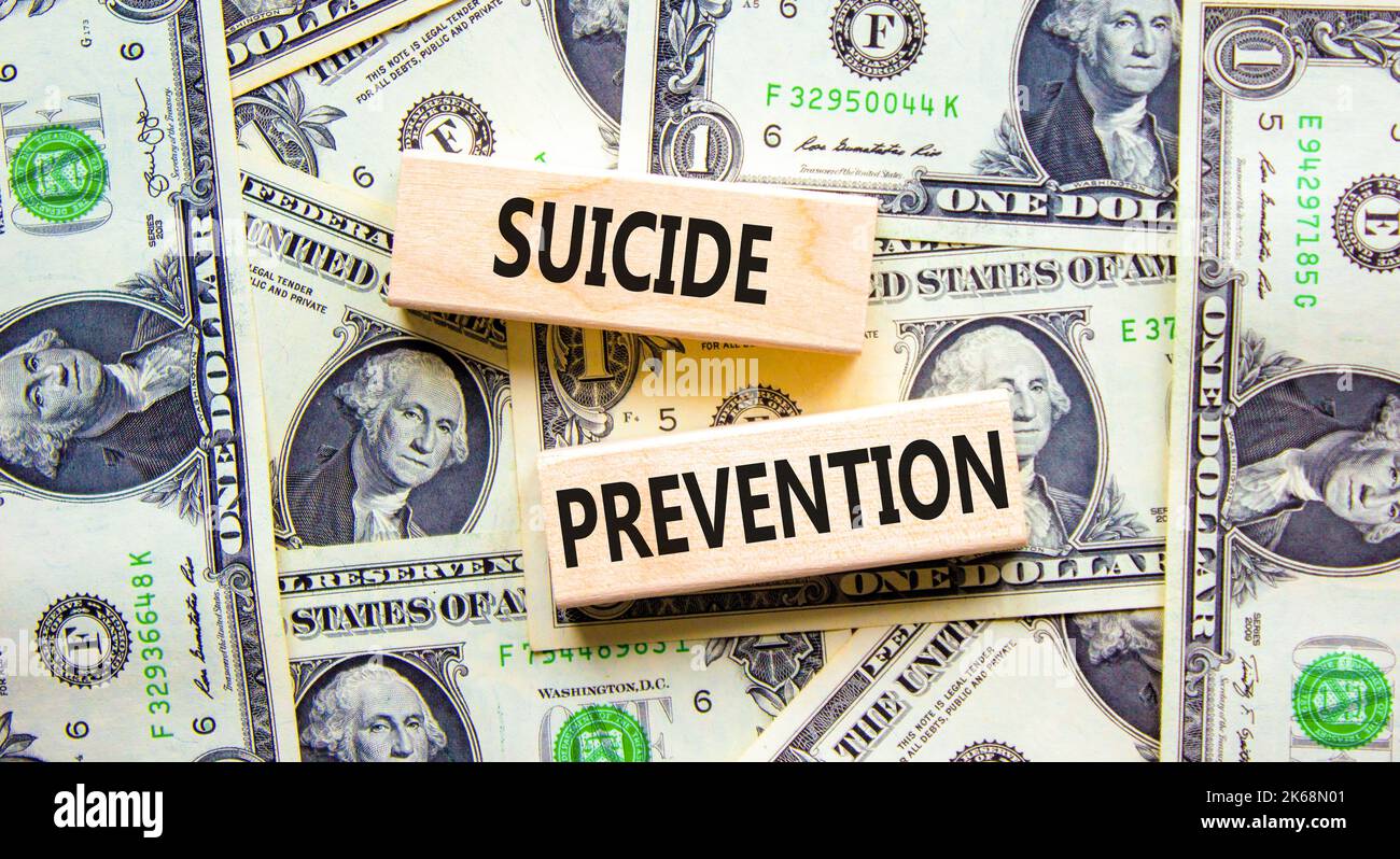 Symbol für die Suizidprävention. Konzept Wörter Selbstmordprävention auf Holzblöcken. Schöner Hintergrund von Dollarscheinen. Psychologische und Selbstmord preven Stockfoto