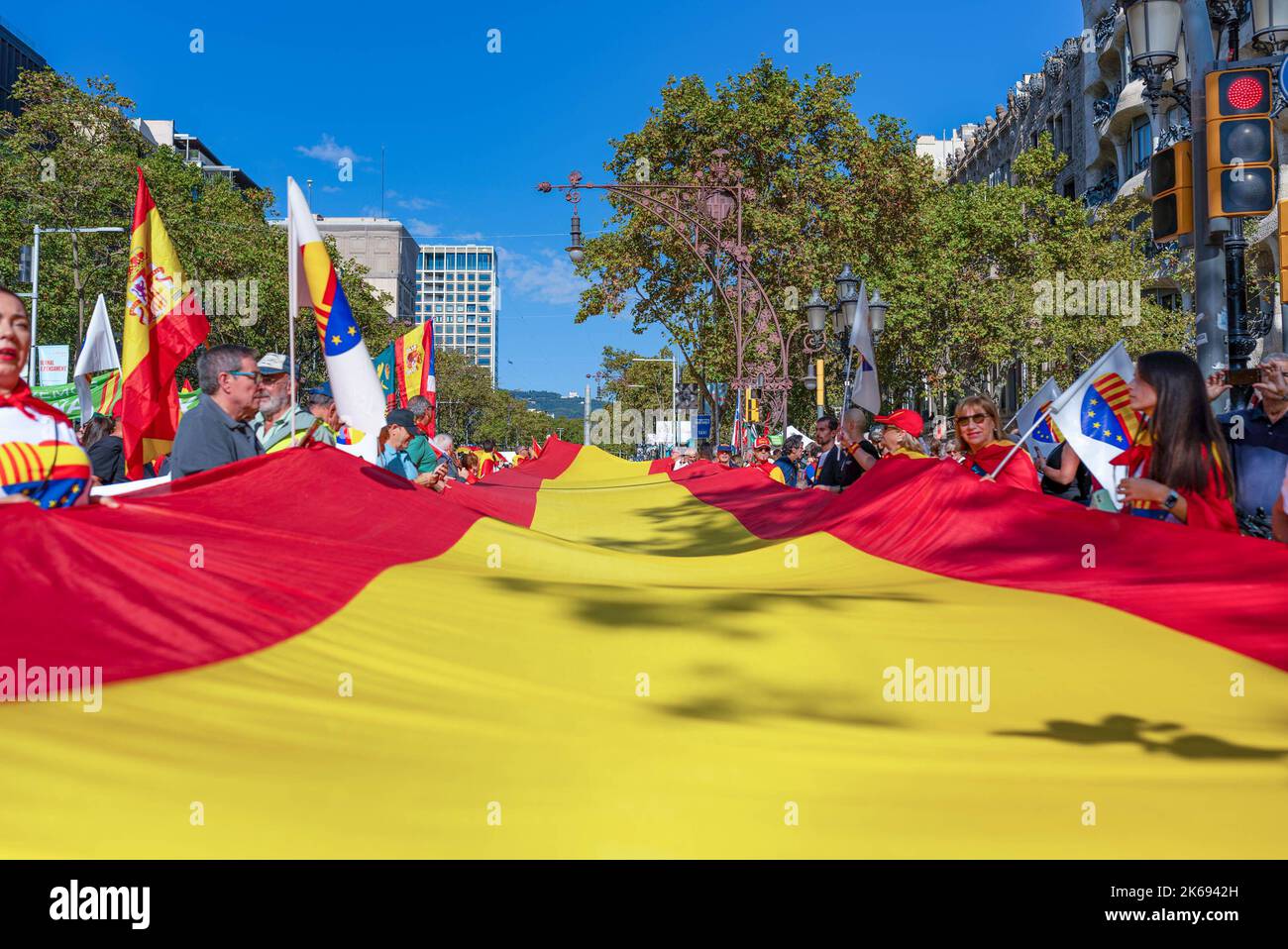 Barcelona, Spanien. 12. Oktober 2022. Während der Parade zum Hispanic Day halten die Menschen eine riesige spanische Flagge. Der Hispanic Day, auf Spanisch bekannt als Dia de España, feiert den Jahrestag des Datums, an dem Christoph Kolumbus in Amerika ankam, wurde aber vor kurzem wegen seiner Feier der Kolonisierung auf den Prüfstand gestellt. Kredit: SOPA Images Limited/Alamy Live Nachrichten Stockfoto