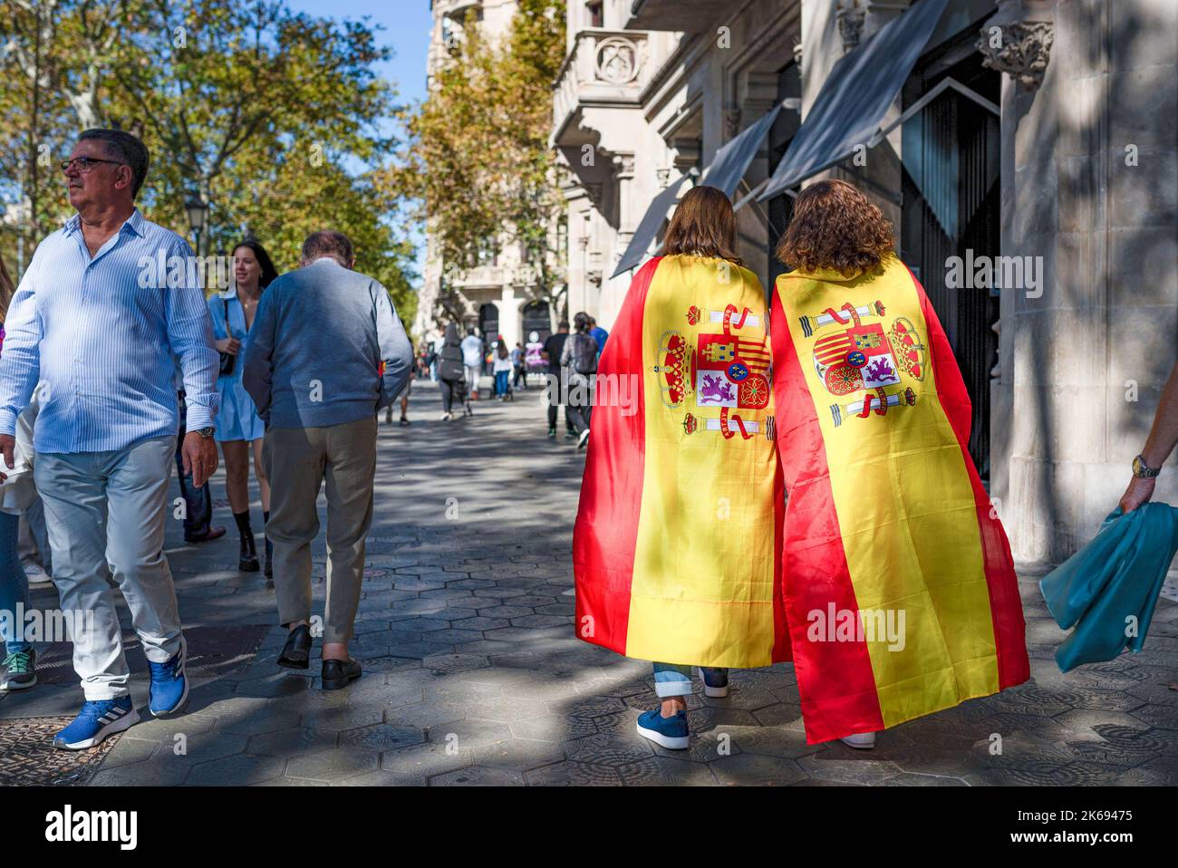 Barcelona, Spanien. 12. Oktober 2022. Frauen, die mit spanischen Flaggen gewickelt sind, gehen während der Parade zum Hispanic Day in den Schatten. Der Hispanic Day, auf Spanisch bekannt als Dia de España, feiert den Jahrestag des Datums, an dem Christoph Kolumbus in Amerika ankam, wurde aber vor kurzem wegen seiner Feier der Kolonisierung auf den Prüfstand gestellt. Kredit: SOPA Images Limited/Alamy Live Nachrichten Stockfoto