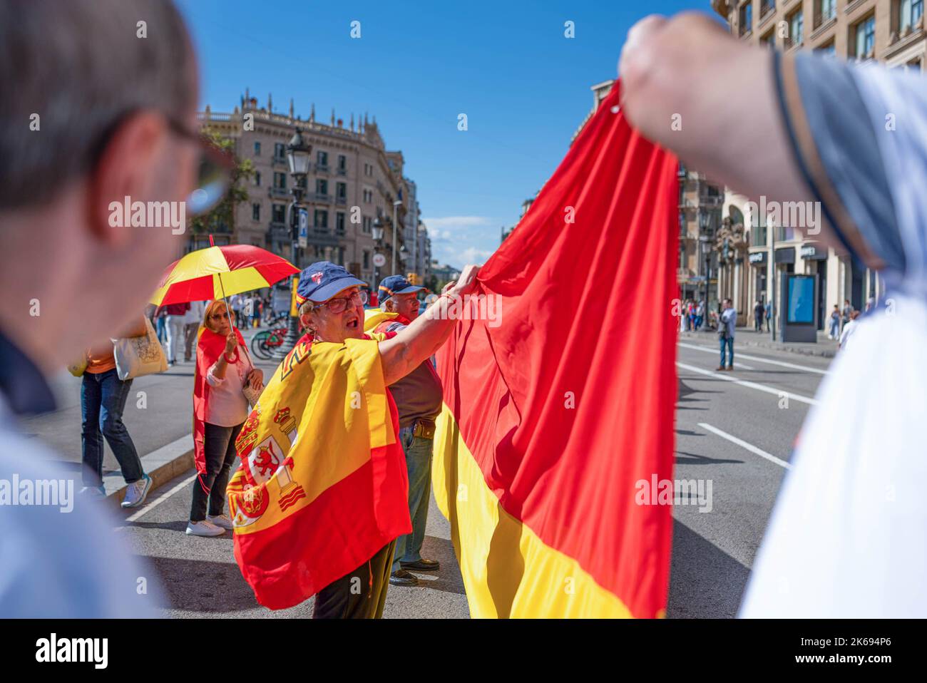 Barcelona, Spanien. 12. Oktober 2022. Während der Parade zum Hispanic Day werden Menschen gesehen, wie sie eine große spanische Flagge falteten. Der Hispanic Day, auf Spanisch bekannt als Dia de España, feiert den Jahrestag des Datums, an dem Christoph Kolumbus in Amerika ankam, wurde aber vor kurzem wegen seiner Feier der Kolonisierung auf den Prüfstand gestellt. (Foto von Davide Bonaldo/SOPA Images/Sipa USA) Quelle: SIPA USA/Alamy Live News Stockfoto