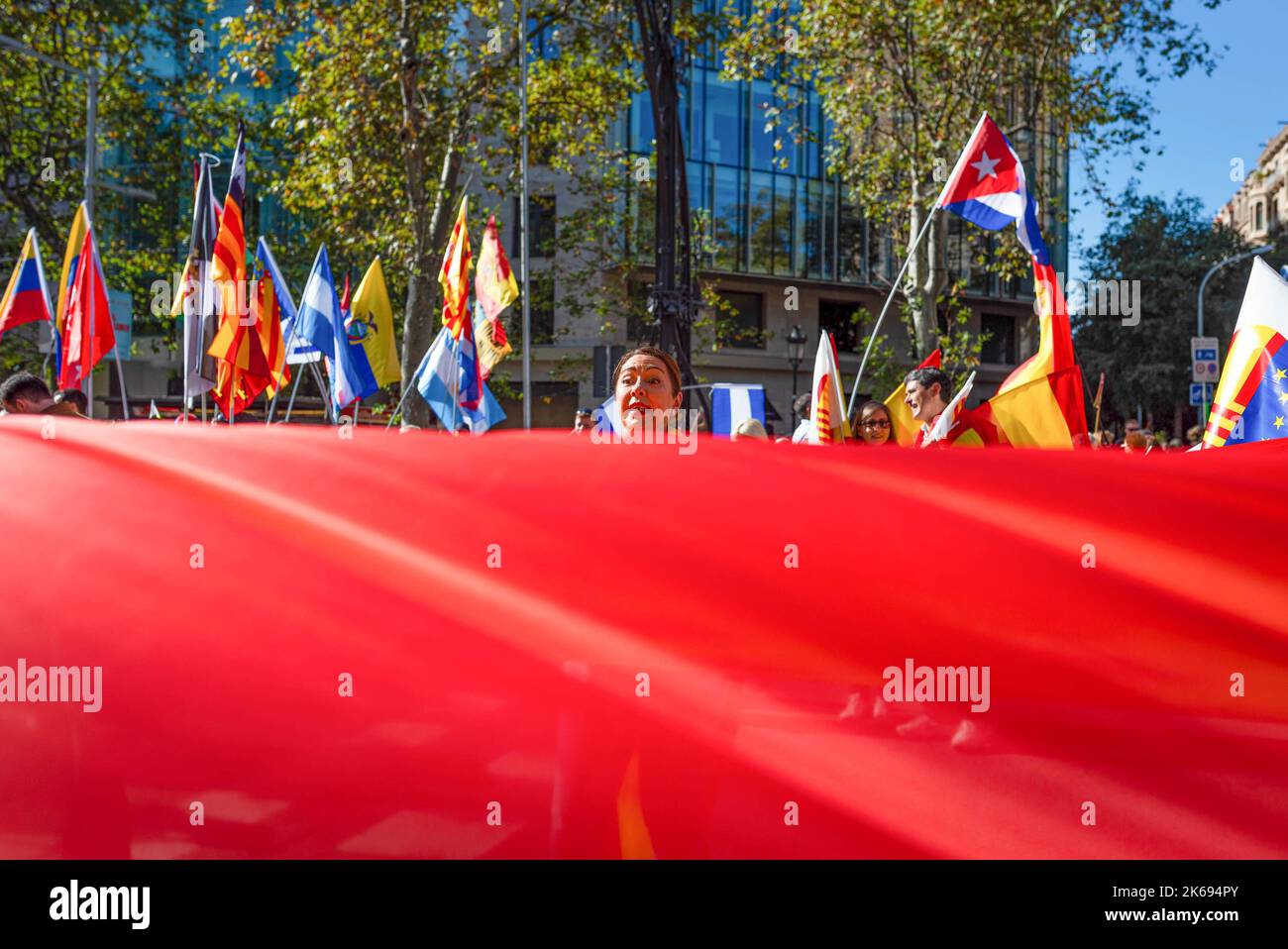 Barcelona, Spanien. 12. Oktober 2022. Während der Parade zum Hispanic Day wird eine Frau gesehen, die hinter einer spanischen Flagge spricht. Der Hispanic Day, auf Spanisch bekannt als Dia de España, feiert den Jahrestag des Datums, an dem Christoph Kolumbus in Amerika ankam, wurde aber vor kurzem wegen seiner Feier der Kolonisierung auf den Prüfstand gestellt. (Foto von Davide Bonaldo/SOPA Images/Sipa USA) Quelle: SIPA USA/Alamy Live News Stockfoto