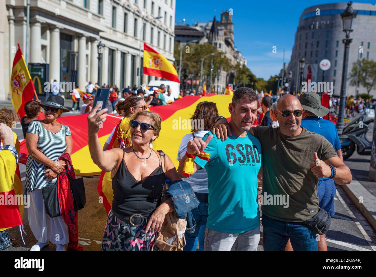 Barcelona, Spanien. 12. Oktober 2022. Während der Parade zum Hispanic Day machen Menschen Selfies vor einer spanischen Flagge. Der Hispanic Day, auf Spanisch bekannt als Dia de España, feiert den Jahrestag des Datums, an dem Christoph Kolumbus in Amerika ankam, wurde aber vor kurzem wegen seiner Feier der Kolonisierung auf den Prüfstand gestellt. (Foto von Davide Bonaldo/SOPA Images/Sipa USA) Quelle: SIPA USA/Alamy Live News Stockfoto