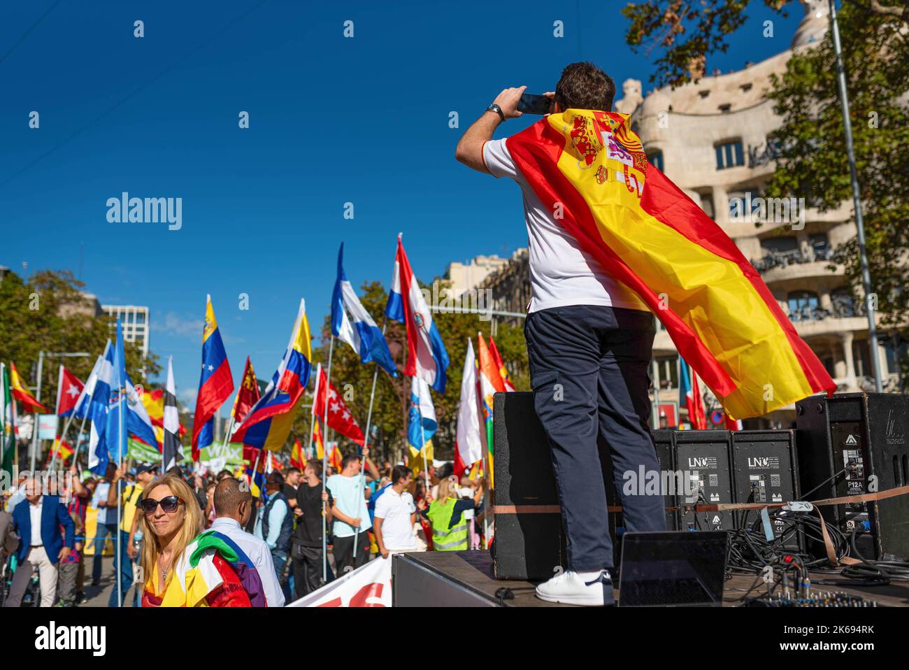 Barcelona, Spanien. 12. Oktober 2022. Während der Parade zum Hispanic Day steht ein Mann, der mit einer spanischen Flagge gehüllt ist, über der Menge. Der Hispanic Day, auf Spanisch bekannt als Dia de España, feiert den Jahrestag des Datums, an dem Christoph Kolumbus in Amerika ankam, wurde aber vor kurzem wegen seiner Feier der Kolonisierung auf den Prüfstand gestellt. (Foto von Davide Bonaldo/SOPA Images/Sipa USA) Quelle: SIPA USA/Alamy Live News Stockfoto