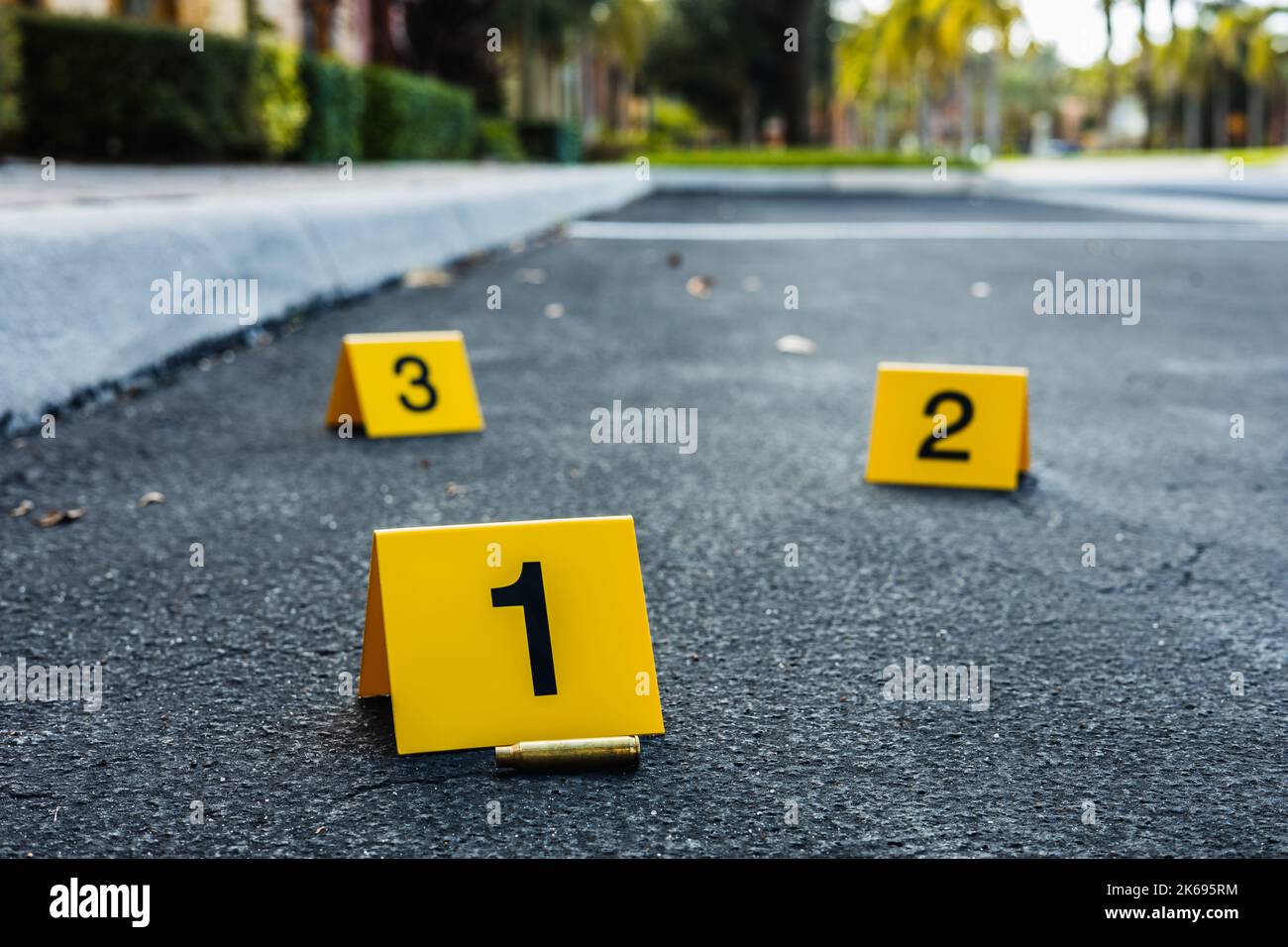 Eine Gruppe gelber Tatort-Beweismarkierungen auf der Straße, nachdem eine Waffe auf ein Patronengewehr geschossen hat Stockfoto