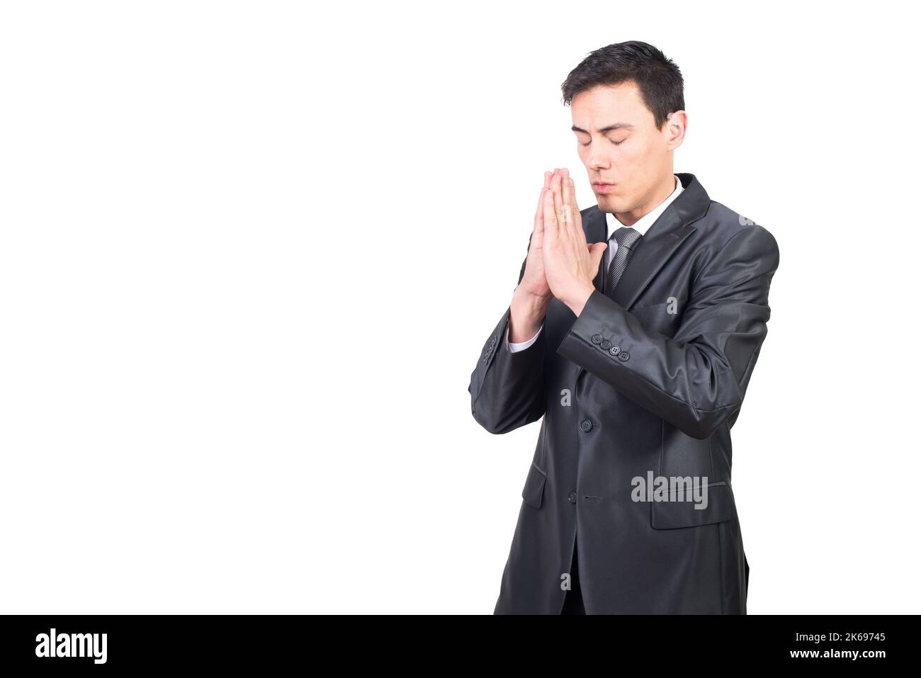 Ernsthafter Mann im schwarzen Anzug, der mit zusammengekrallten Händen betet Stockfoto