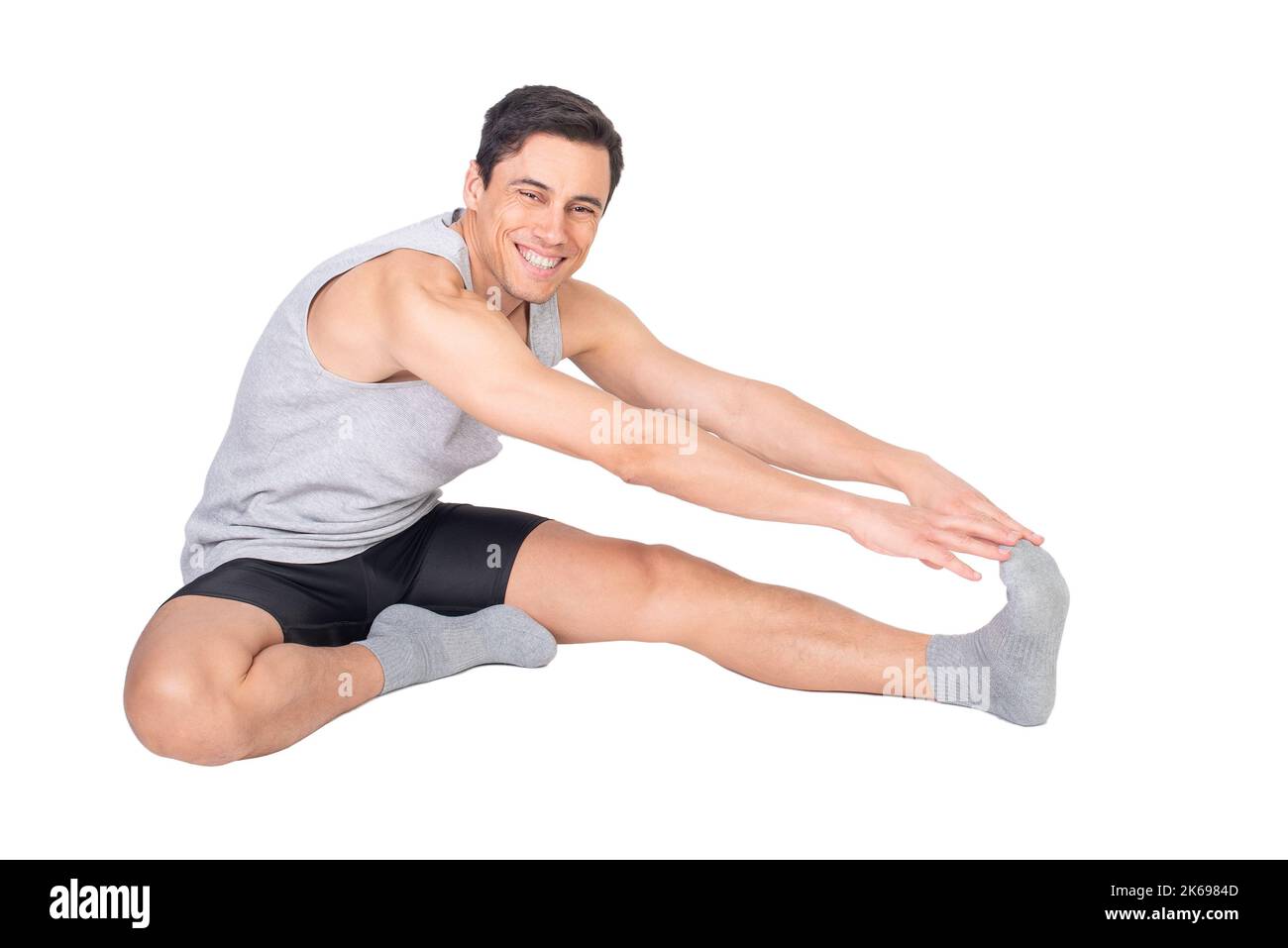 Glücklicher Sportler, der im Studio den Oberschenkelmuskel dehnt Stockfoto