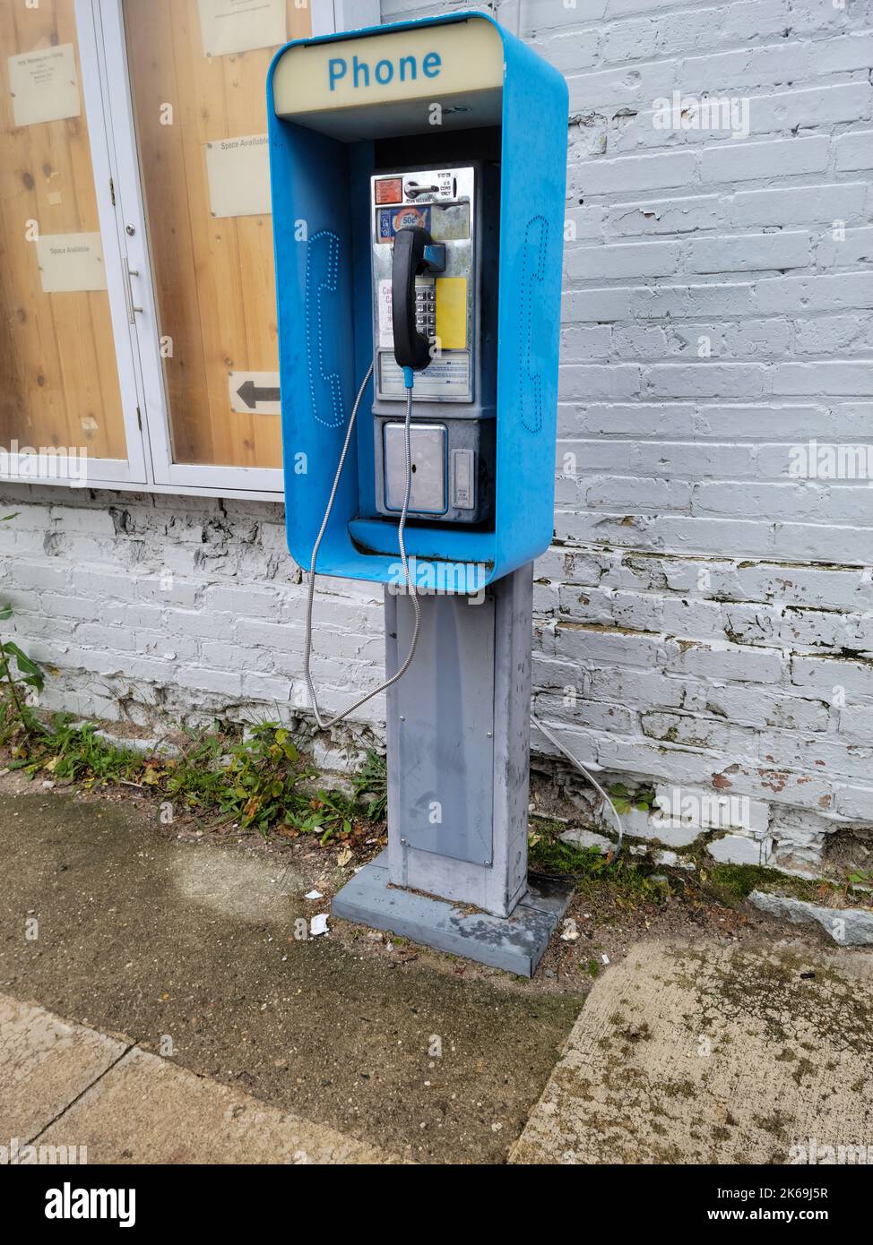 Bezahltelefon im Freien mit Kabel durch ein altes Ziegelgebäude Stockfoto