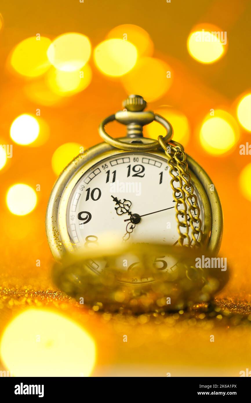Weihnachtszeit.Goldene Uhr in Gold Glitter auf einem gelben Hintergrund mit leuchtenden Bokeh.Weihnachtszeit.Weihnachtstapete.Feiertagslichter.schön Stockfoto