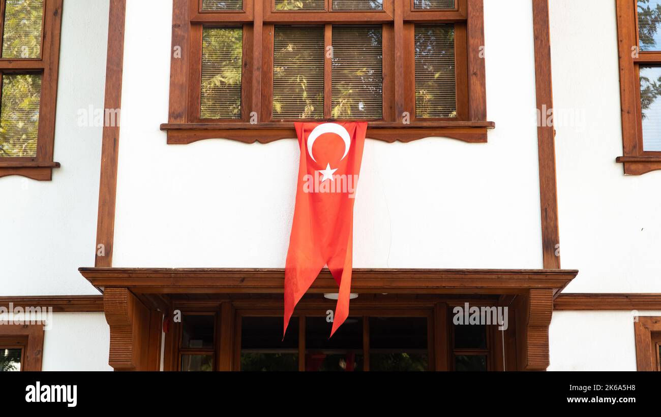 Türkische Flagge hängt am Fenster eines traditionellen türkischen Hauses. Wir feiern den 29. Oktober oder den 23. April, den 30. August. Türkisches nationales Urlaubskonzept. Stockfoto