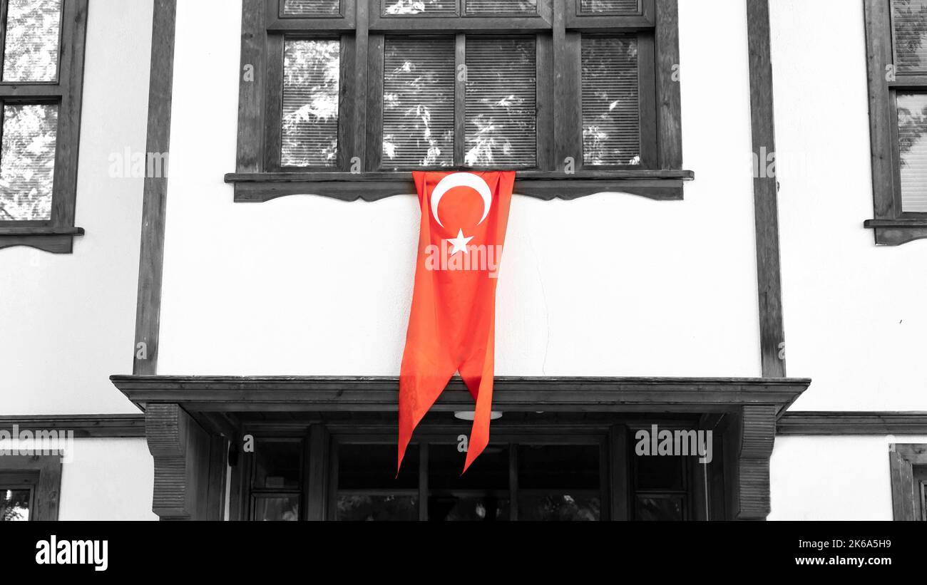 Türkische Flagge hängt am Fenster eines traditionellen türkischen Hauses. Wir feiern den 29. Oktober oder den 23. April, den 30. August. Türkisches nationales Urlaubskonzept. Stockfoto