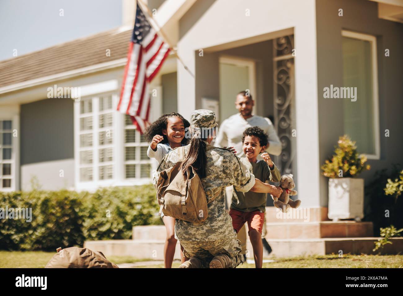 Die Servicefrau umarmte ihre Kinder, nachdem sie von der Armee nach Hause kam. Die amerikanische Soldatin wurde von ihrem Mann und ihren Kindern herzlich willkommen geheißen. Militär w Stockfoto