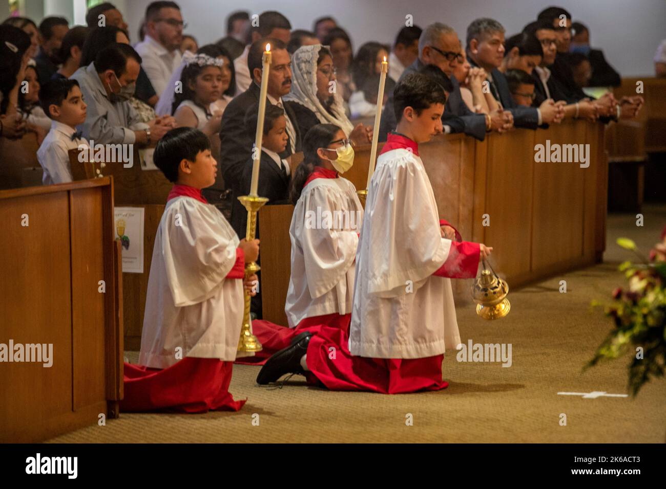 Auf den Knien nehmen multirassische Altarjungen an einer katholischen Messe in Tustin, CA, Teil. Stockfoto