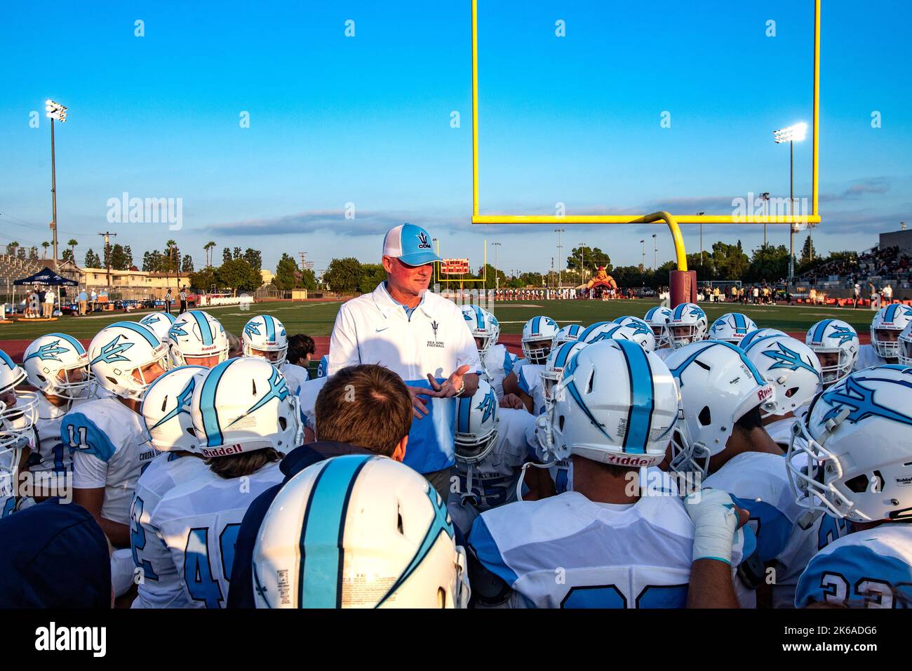 Vor einem Spiel in Downey, CA, hält ein Fußballtrainer der Highschool ein Pep-Gespräch mit seinen Spielern ab. Stockfoto