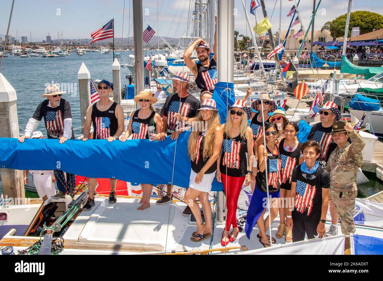 Multirassische Crew und Passagiere eines Segelbootmodells mit US-Flagge T-Shirts bei einer Bootsparade am 4. Juli in Newport Beach, CA. Stockfoto