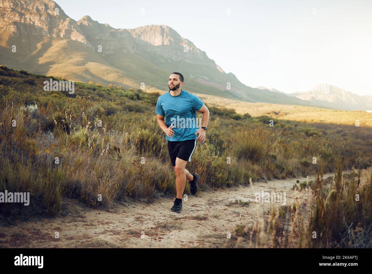 Gesundheit, Berg und Mann laufen in der Natur für Fitness, Training und Sport. Workout, Wellness und Sommer mit Athlet Runner im Grasfeld Stockfoto