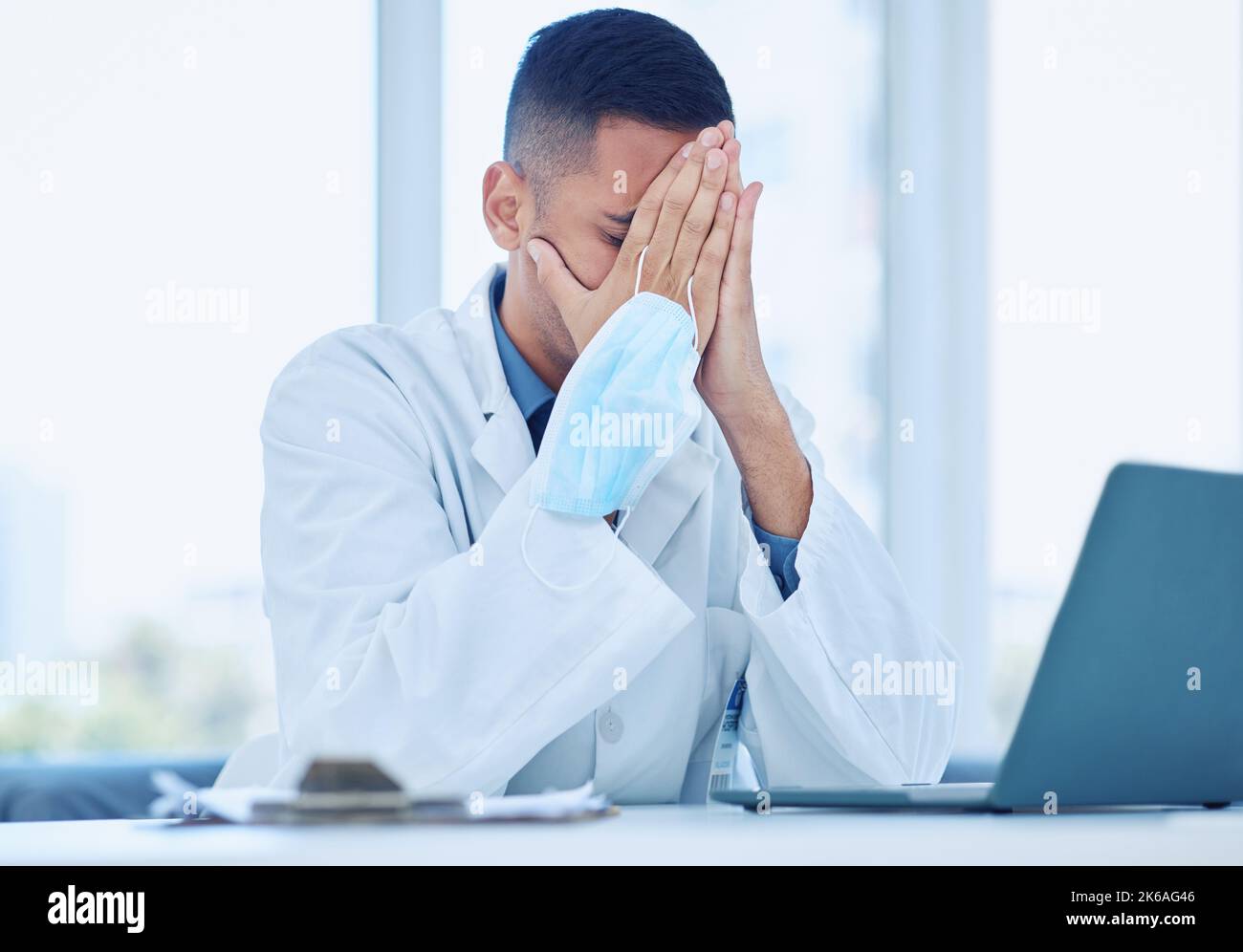 Covid Arzt, müde von Maske im Büro von Stress und Kopfschmerzen aus covid19 Patienteninformationen Bericht Ergebnisse auf Laptop. Arzt Stockfoto