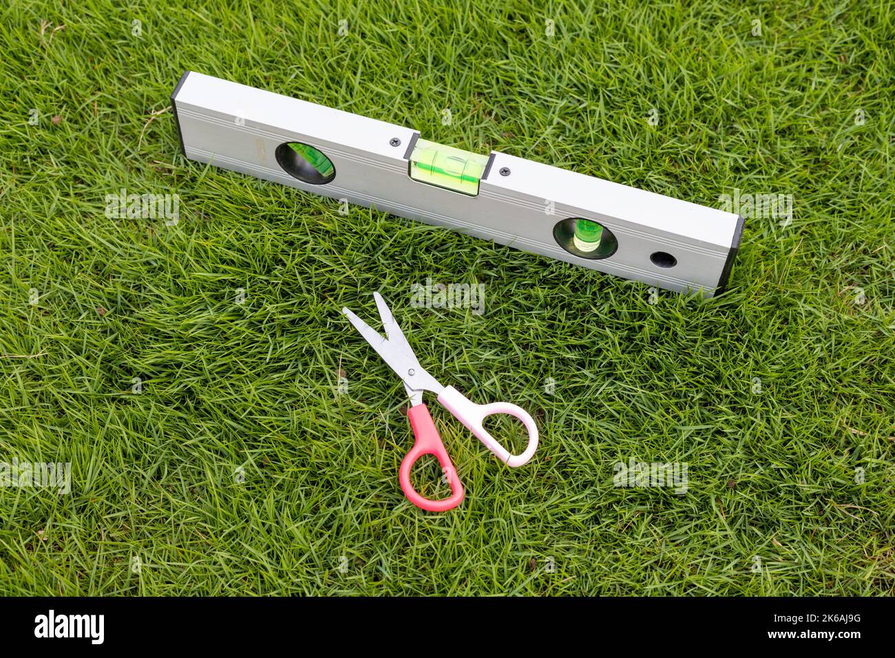 Gras schneiden mit einer Schere und mit dem Nivellierwerkzeug, um das Gras perfekt zu waagerecht zu schneiden Stockfoto