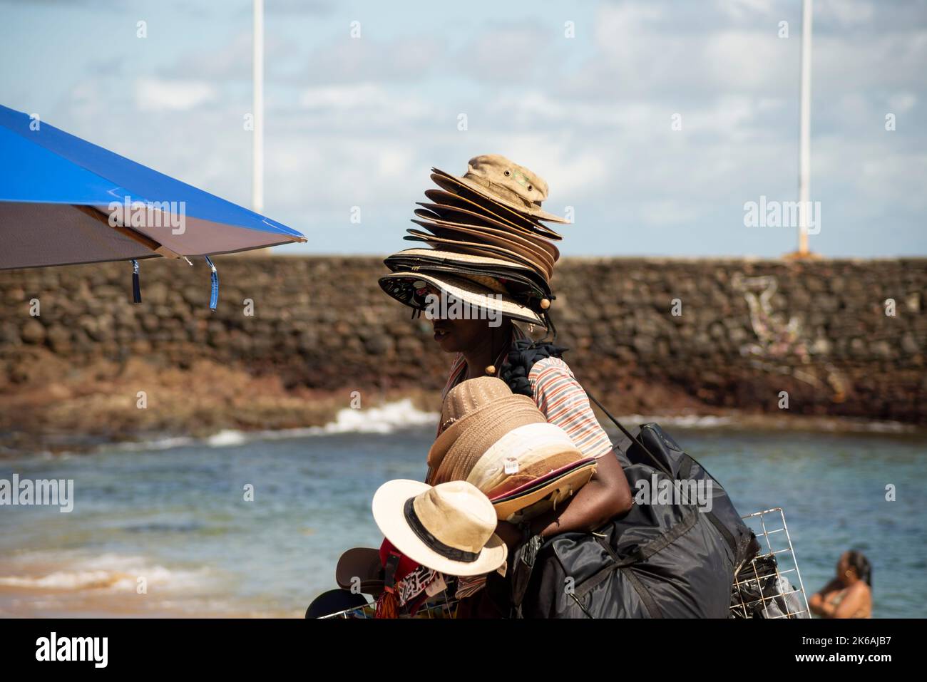Salvador, Bahia, Brasilien - 04. Juni 2022: Straßenverkäufer laufen auf dem Sand des Strandes von Porto da Barra in Salvador, Bahia. Stockfoto