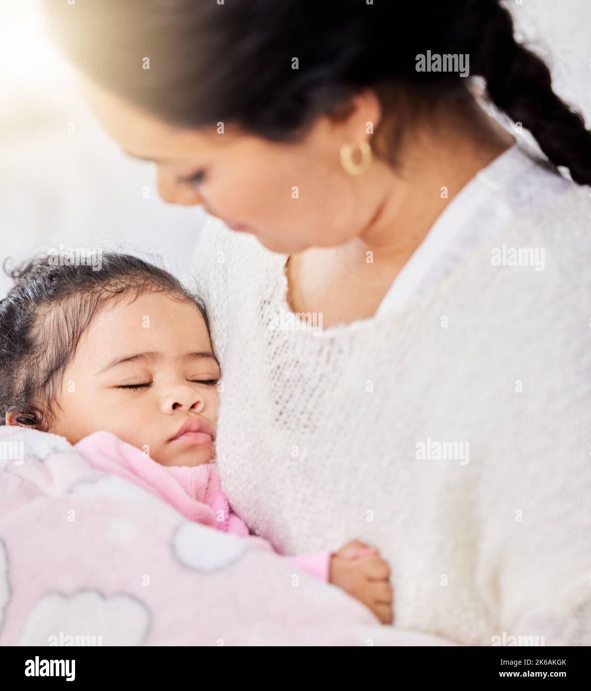 Liebenswert kleines Mädchen Gefühl warm und sicher, während friedlich schlafen in ihren liebevollen Armen Mutter zu Hause. Fürsorgliche Mutter hält und schaukelt sie niedlich Stockfoto