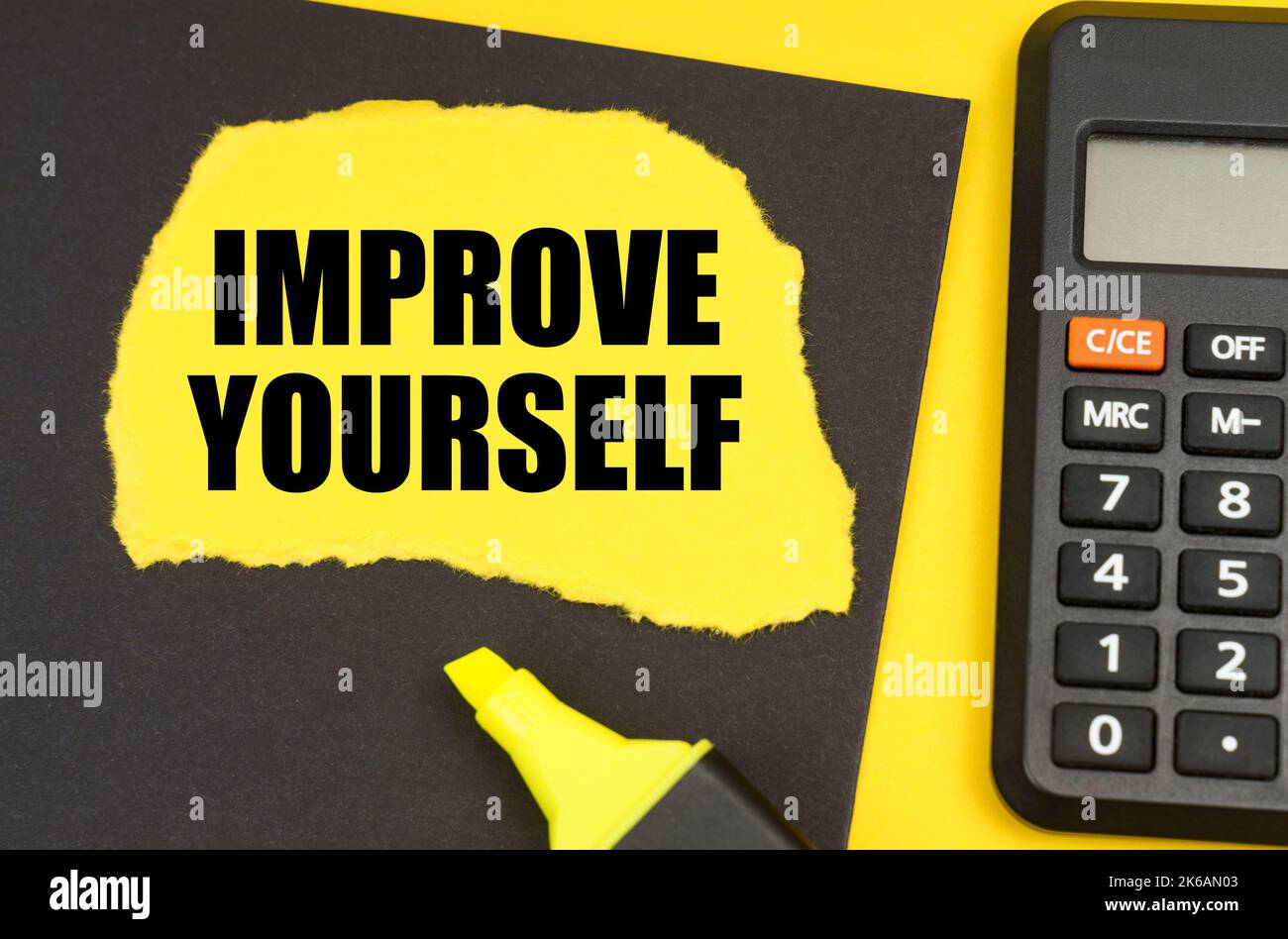 Geschäftskonzept. Auf gelbem Hintergrund ein Taschenrechner, ein schwarzes Blatt, ein Marker und ein gelbes zerrissenes Blatt mit der Aufschrift - VERBESSERN SIE SICH Stockfoto