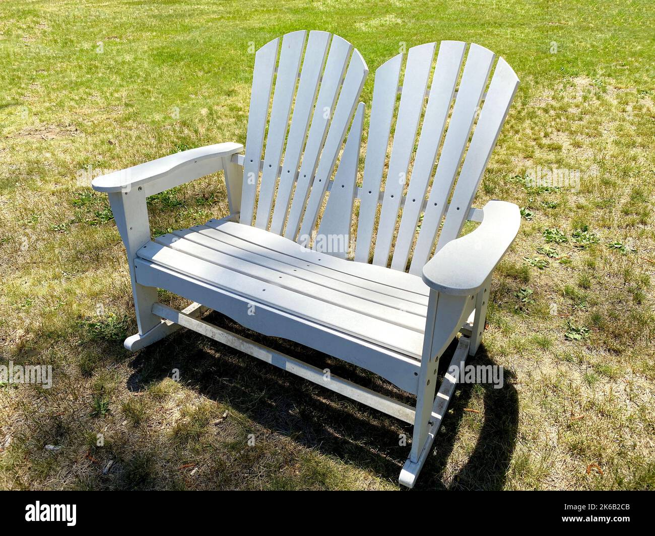 Ein weißer Hinterhof Lounge Stühle schattig entspannend Gras Rasen alter Stuhl Sitzgelegenheiten Garten Gras Schatten Bäume Retro-Design Vintage-Stil Holz Strand im Freien Armlehne Stockfoto