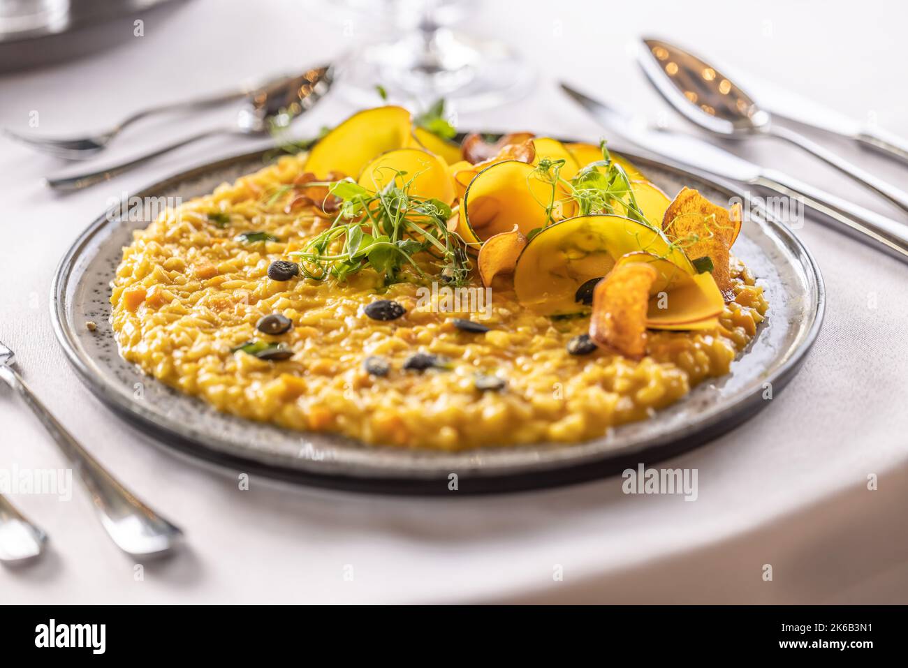 Kreativ zubereitetes Kürbisrisotto, serviert auf einem feierlich zubereiteten Tisch im Hotelrestaurant. Stockfoto