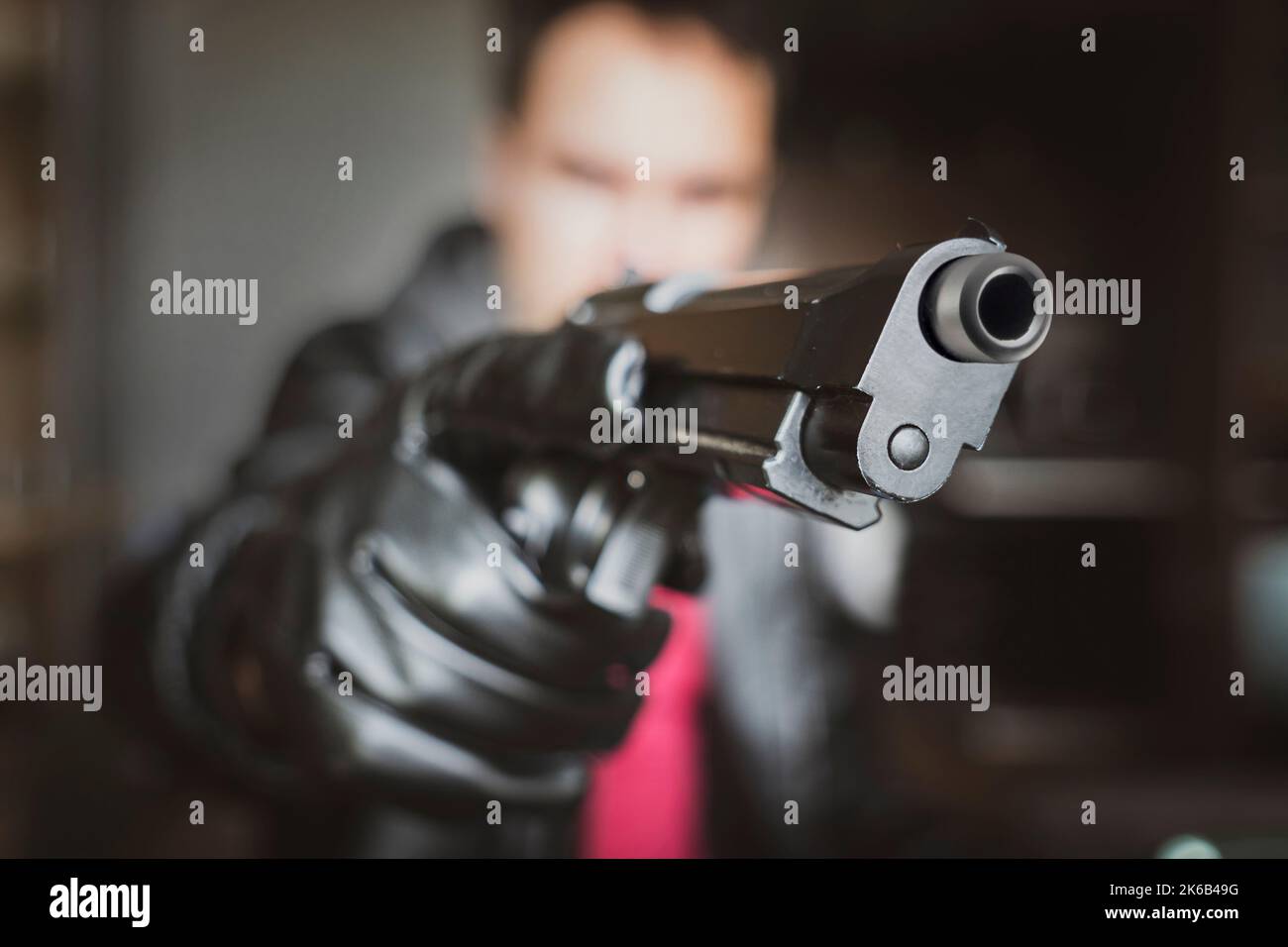 Ein Mann, Polizist oder Räuber, Gangster, der seine Waffe versteckt. Der Schütze zielt durch den Anblick. Konzentrieren Sie sich auf den Lauf der Waffe. Stockfoto