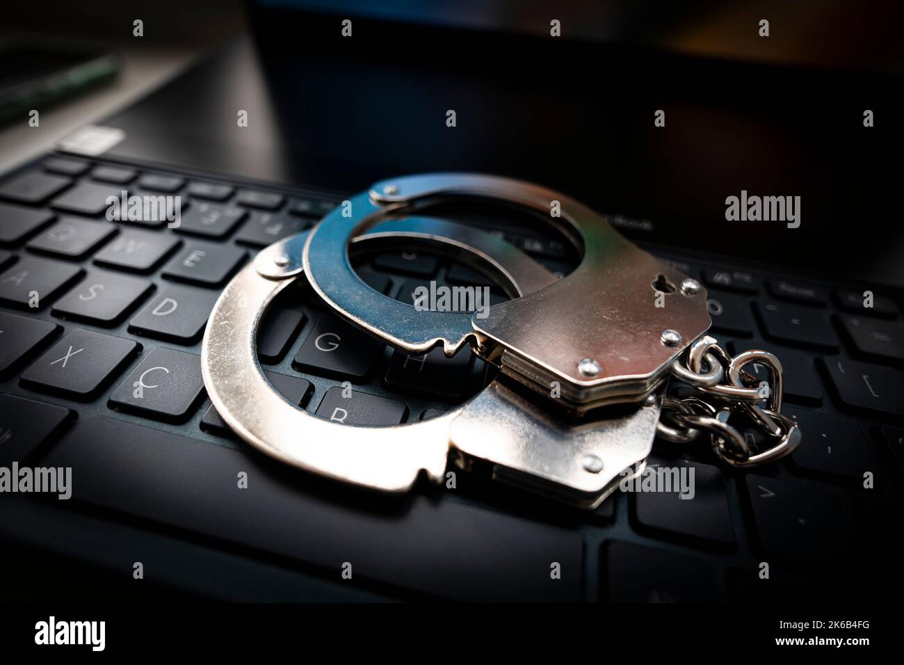 Computertastatur und Handschellen. Konzept für Cyberkriminalität, Internetsicherheit und Kriminalität. Metallhandschellen auf einer schwarzen Tastatur. Stockfoto