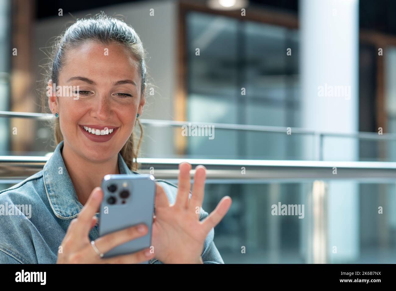 Junge Frau mit Mobiltelefon in einem modernen Büro - Stock Foto Stockfoto
