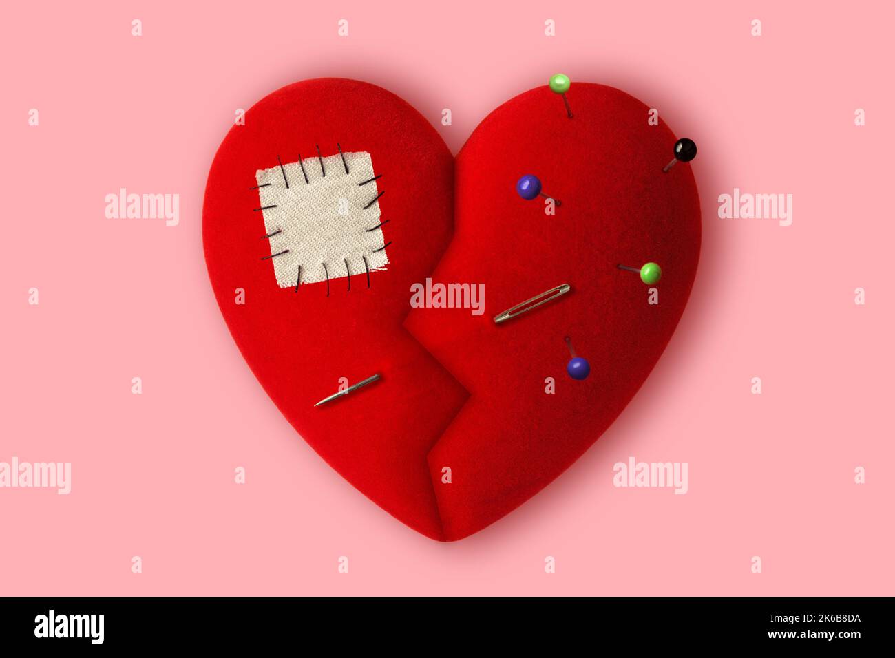 Gebrochenes Herz mit Nadeln, Nähnadel und Patch auf rosa Hintergrund - Konzept der Heilung eines gebrochenen Herzens Stockfoto