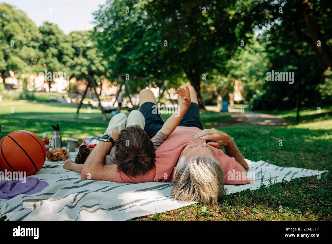 Großvater und Enkel liegen auf einer Picknickdecke im Park Stockfoto