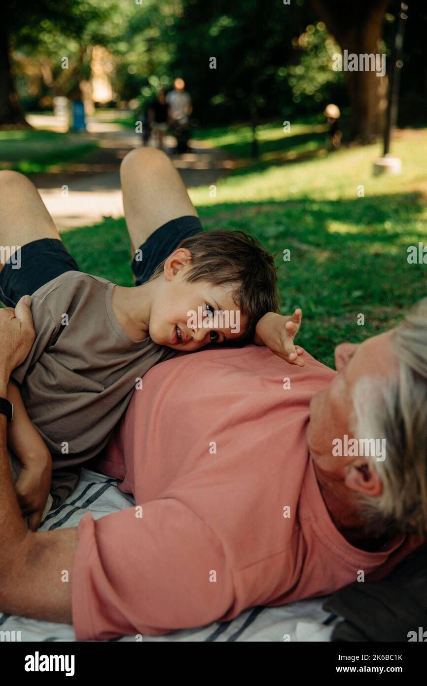 Enkel im Gespräch mit Großvater, der im Park liegt Stockfoto