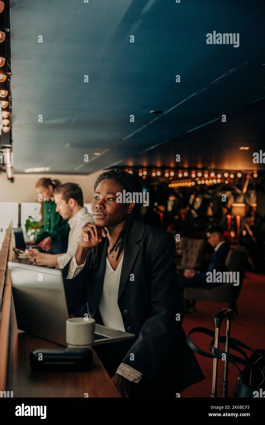 Nachdenkliche junge Geschäftsfrau, die mit der Hand am Kinn in der Hotellounge sitzt Stockfoto