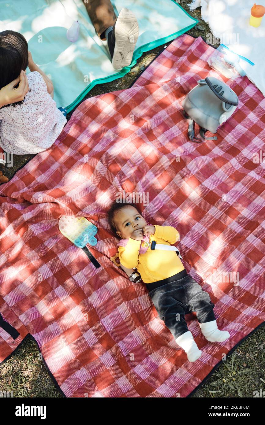 Direkt über der Aufnahme eines kleinen Mädchens, das auf einer karierten Picknickdecke liegt Stockfoto Direkt über der Aufnahme eines kleinen Mädchens, das auf einer karierten Picknickdecke liegt Stockfoto