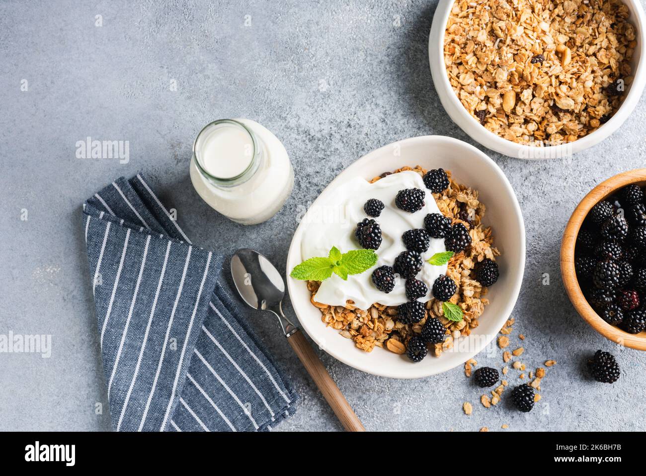 Frühstücksgranola Schüssel mit Joghurt und Brombeeren auf Beton Hintergrund Tisch. Draufsicht, Kopierbereich Stockfoto