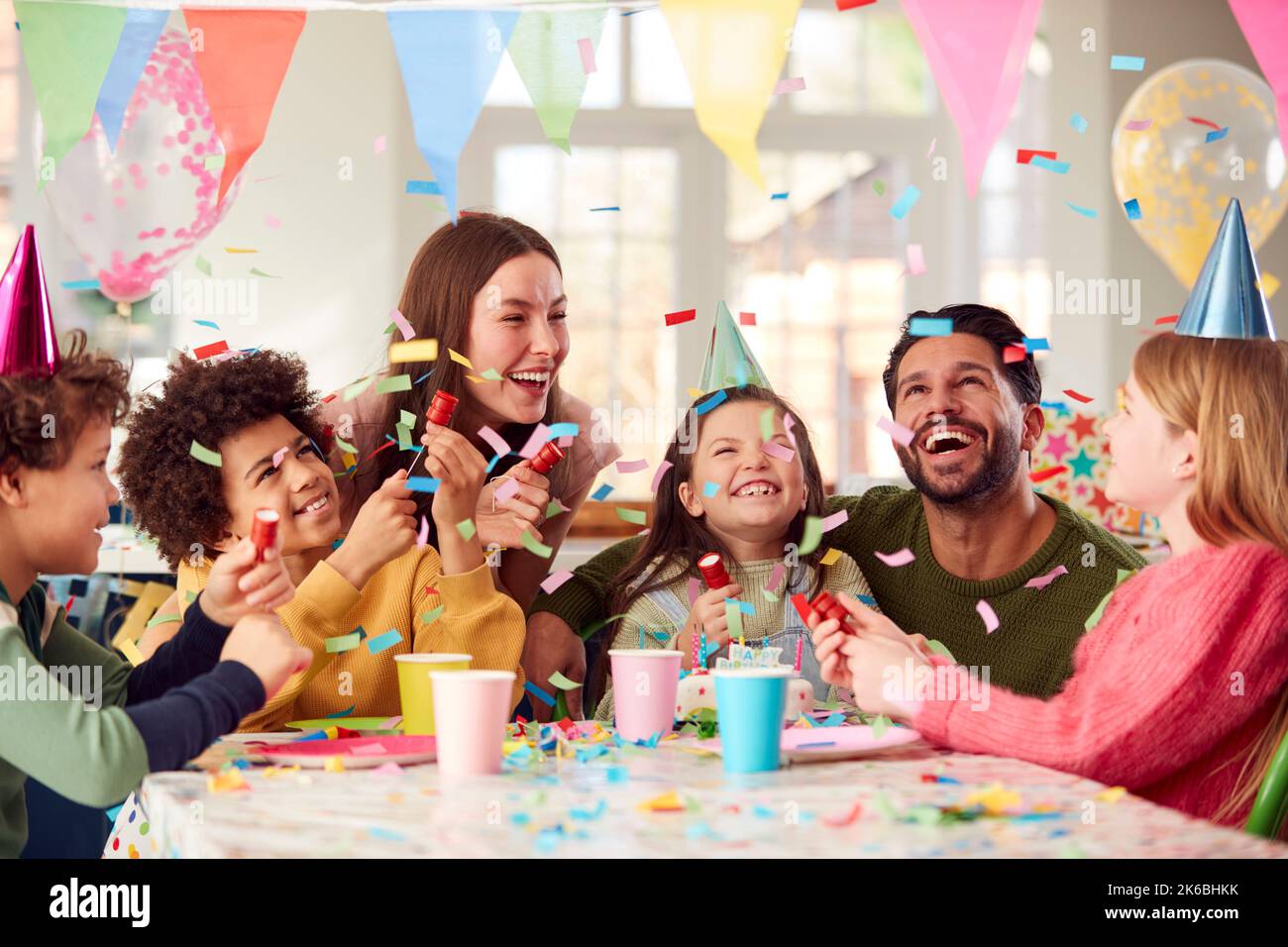 Mädchen Mit Eltern Und Freunden Zu Hause Feiert Geburtstag Feuern Konfetti Poppers Auf Party Stockfoto