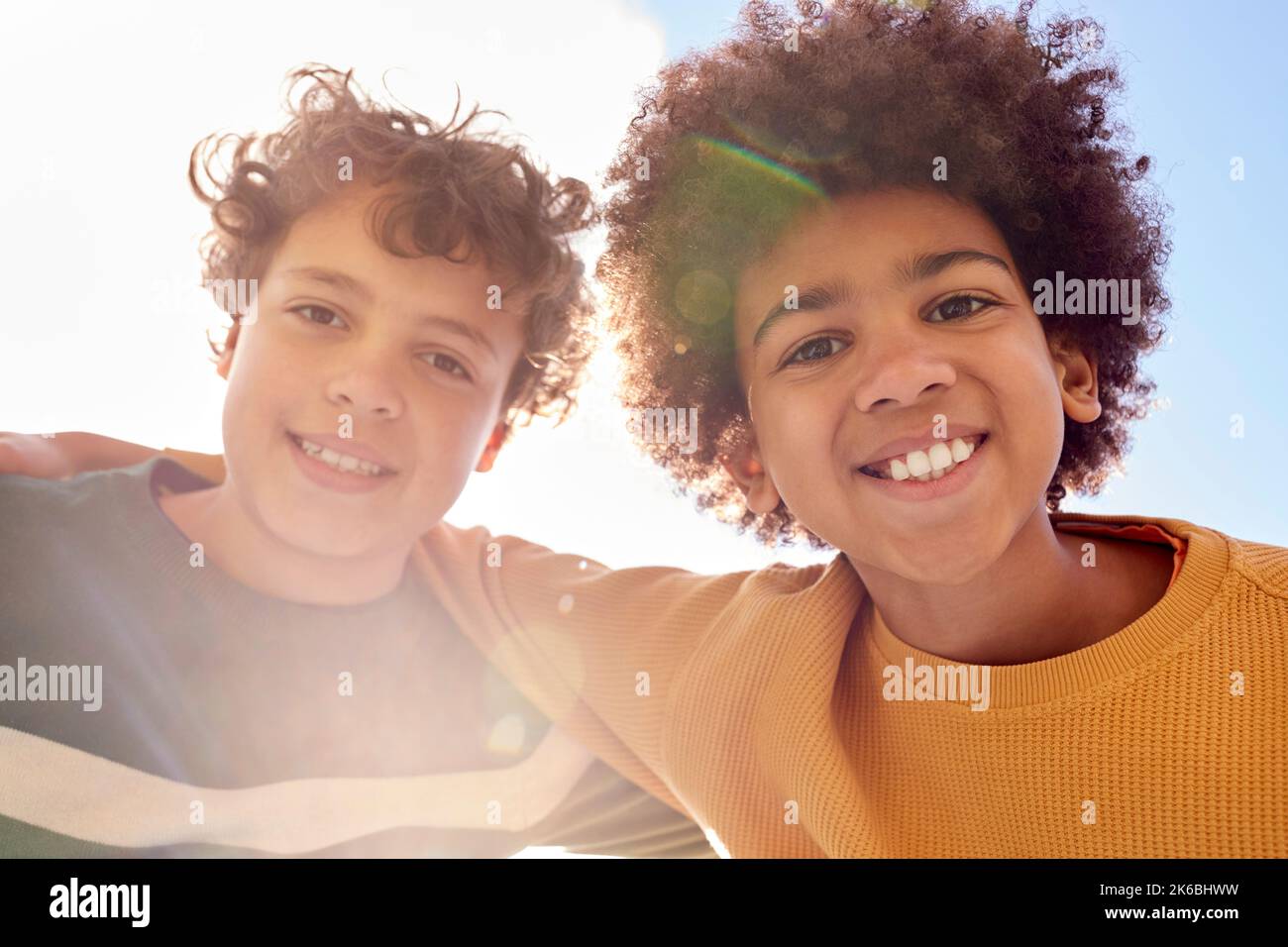 Low-Angle-Porträt Von Zwei Jungen, Die Spaß Am Spielen Im Freien Haben Und Mit Lens Flare In Die Kamera Blicken Stockfoto