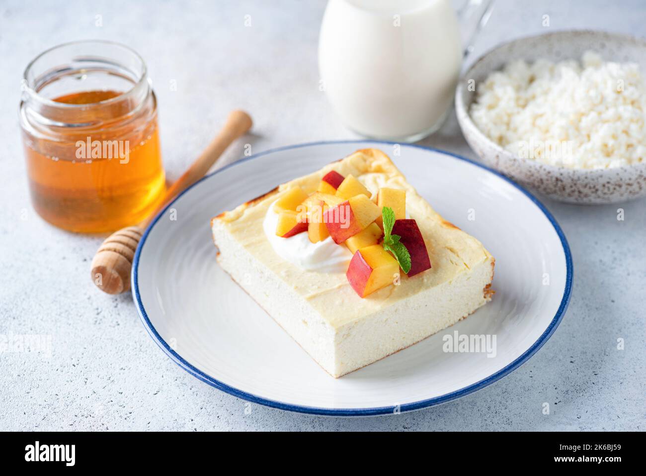Quark-Auflauf Zapekanka mit Pfirsich, Sauerrahm und Honig. Süßes Frühstück Käsekuchen Stockfoto