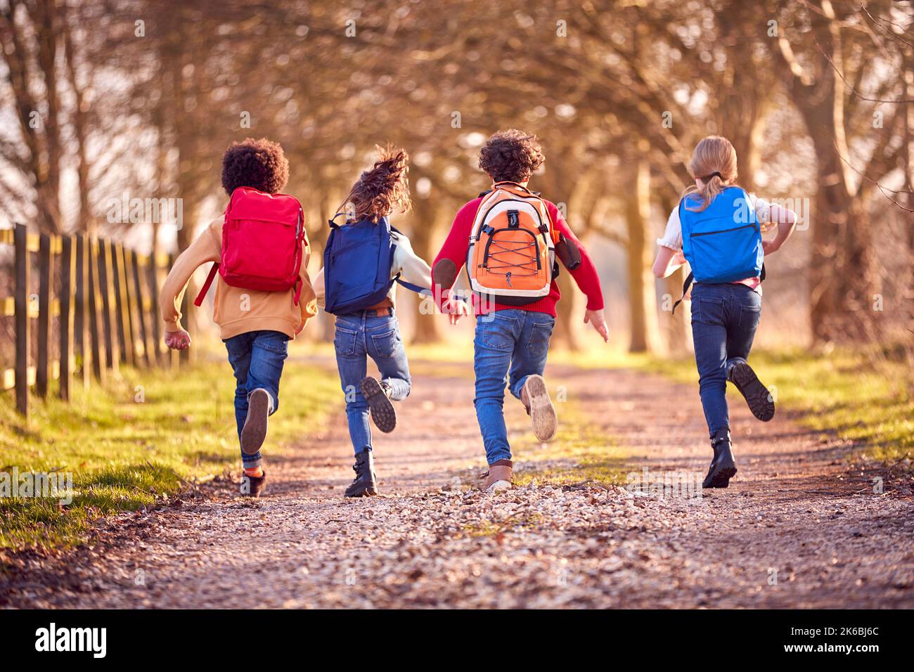 Rückansicht Von Kindern Mit Schulrucksäcken Im Freien, Die Auf Dem Countryside Track Laufen Stockfoto