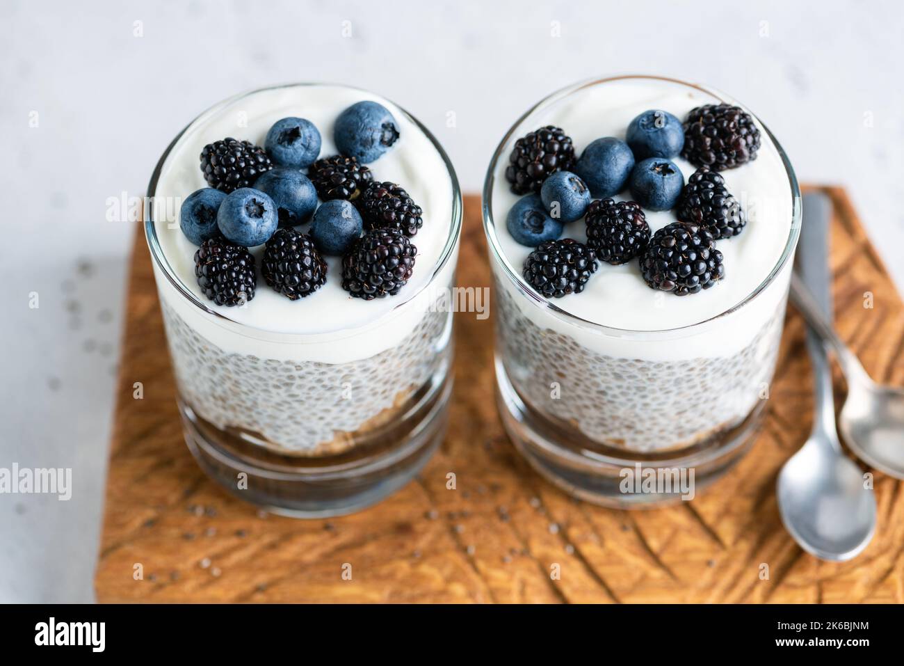 Chia Pudding mit griechischem Joghurt und Beeren im Glas auf einem Holzbrett. Nahaufnahme. Gesunde Ernährung Lebensmittel, die reich an Kalzium und Omega-3-Fettsäuren Stockfoto