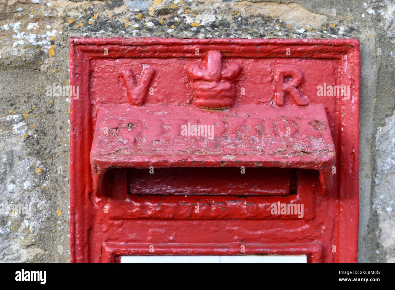 Nahaufnahme der rot bemalten britischen Royal Mail Briefkasten draußen in einer Straße, mit Queens Krone und Initialen V R. Briefkasten ist der britische Monarch Victoria Stockfoto
