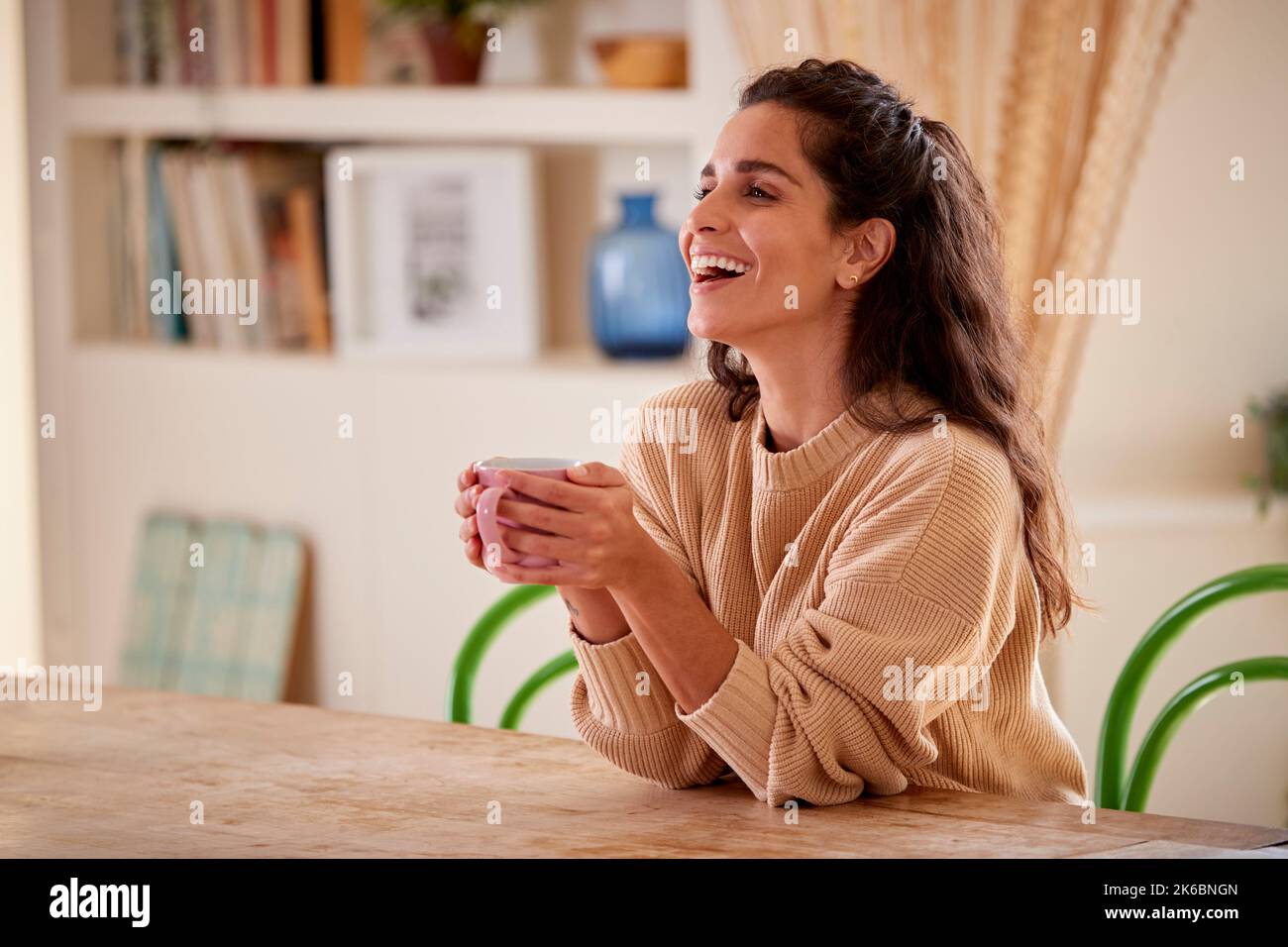 Frau, Die Sich Zu Hause Entspannt Und Am Tisch Mit Einem Heißen Getränk Sitzt Stockfoto