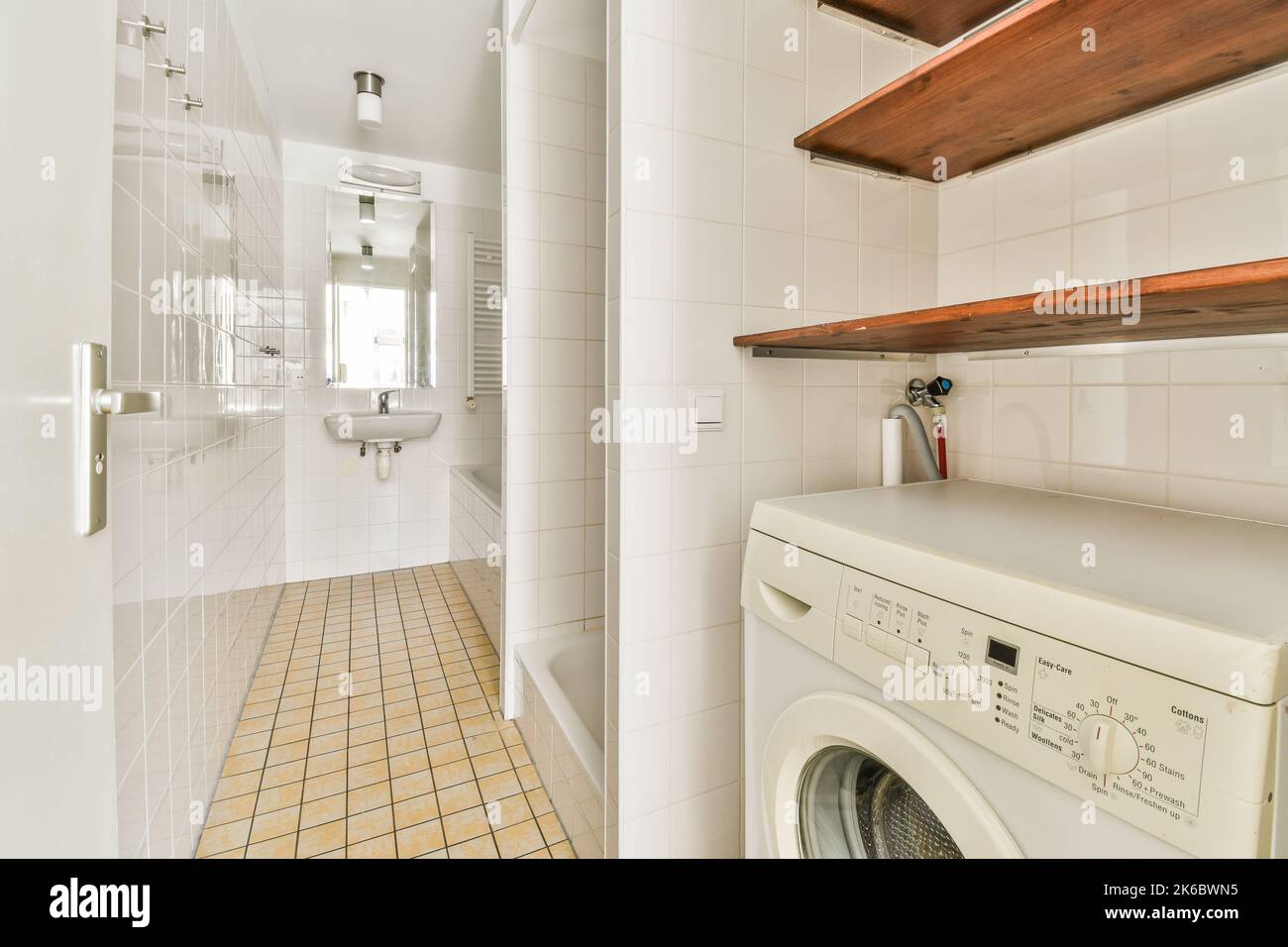 Dusche und freistehendes Badezimmer im hellen Badezimmer mit Waschmaschine Stockfoto