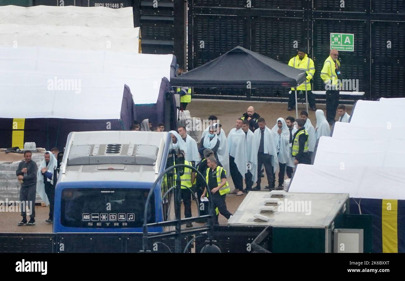 Eine Gruppe von Menschen, die als Migranten gedacht wurden, durchläuft das Grenztruppengelände in Dover, Kent, um an Bord von Bussen zu gehen, nachdem sie gestern von Schiffen der Grenztruppen nach kleinen Bootsvorfällen im Kanal gebracht wurden. Bilddatum: Donnerstag, 13. Oktober 2022. Stockfoto