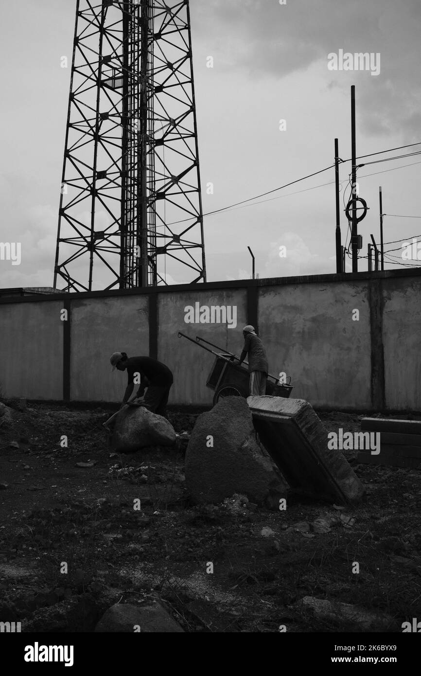 Cikancung, West Java, Indonesien - 06. Oktober, 2022 : Monochromes Foto, Foto von Bauarbeitern, die Steine mit einem Wagen trugen Stockfoto