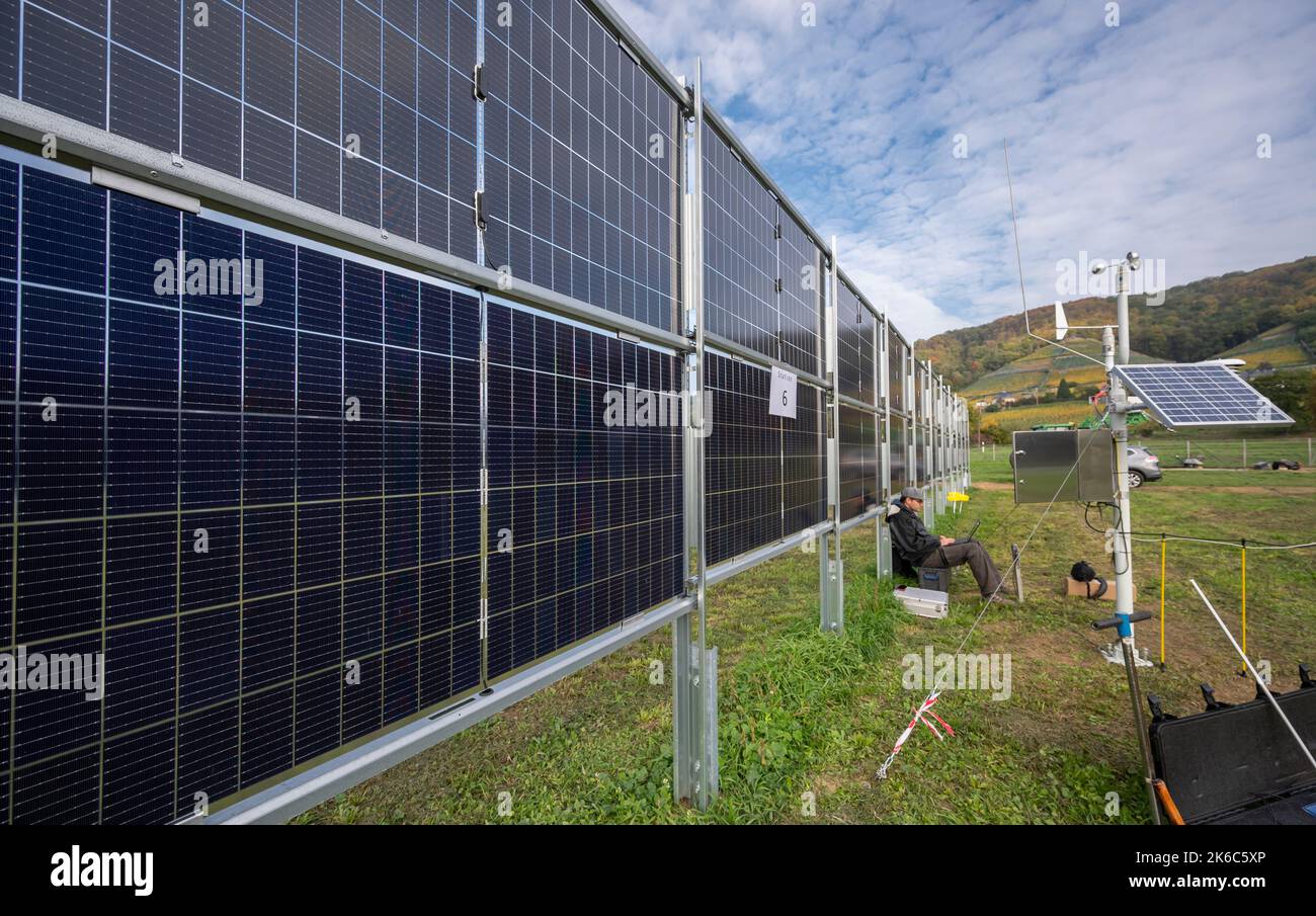 Dresden, Deutschland. 13. Oktober 2022. Marc Heinrich vom Deutschen Wetterdienst DWD Potsdam sitzt mit einem Laptop an einer mobilen Messstation der Agrar-Photovoltaik-Anlage an der Hochschule Dresden. Die Solaranlage wurde im Rahmen eines Forschungsprojekts an der HTW Dresden errichtet. Das Projekt zielt darauf ab, die Möglichkeiten der Verwendung doppelseitiger, vertikal montierter Module auf Ackerflächen zu untersuchen und weiterzuentwickeln. Quelle: Matthias Rietschel/dpa-Zentralbild/ZB/dpa/Alamy Live News Stockfoto